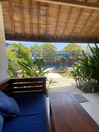 a room with a bed and a table and an umbrella at Indigo Bungalows in Gili Trawangan
