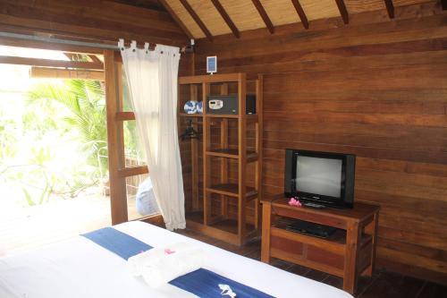 a bedroom with a bed and a tv on a wooden wall at Indigo Bungalows in Gili Trawangan