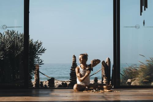 a man sitting on the floor in front of a window at Paradis Plage Surf Yoga & Spa in Taghazout