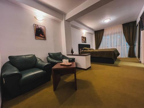ein Wohnzimmer mit einem Sofa, einem Bett und einem Tisch in der Unterkunft Silvia Chalet Poiana Brasov in Braşov
