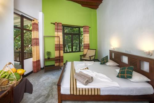 a bedroom with a large bed with green walls at VillaWatuna in Unawatuna