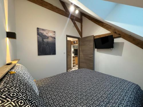 een slaapkamer met een bed en een flatscreen-tv bij Gîte Au Creux Du Moulin in Bussang