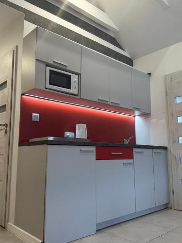 a kitchen with white cabinets and a microwave at Apartamenty Olimpijskie Szczyrk in Szczyrk