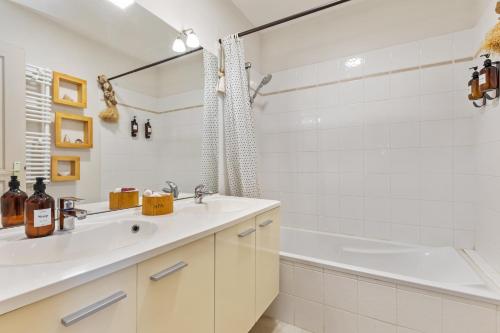La salle de bains blanche est pourvue d'un lavabo et d'une baignoire. dans l'établissement Un Rêve d'ailleurs, à Cers