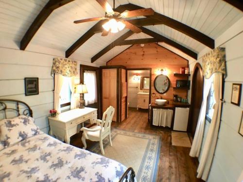 Schlafzimmer mit einem Bett, einem Schreibtisch und einem Deckenventilator in der Unterkunft Tiny Home Cottage Near the Smokies #7 Tilly in Sevierville