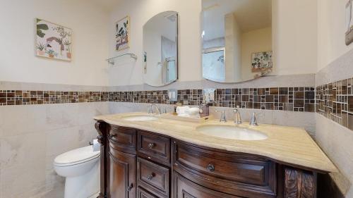 a bathroom with a sink and a toilet and mirrors at Dazzling Westside 4 Br Home-minutes To The Beach in Los Angeles