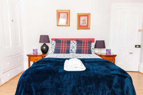 a bedroom with a bed with a blue blanket and two tables at Thirty Barons in Portsmouth