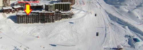 a ski slope with a building in the snow at Residence Tourotel in Val Thorens