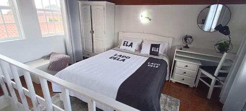 a white bedroom with a bed and a desk at Alojamento Bela Vista in Lajes do Pico