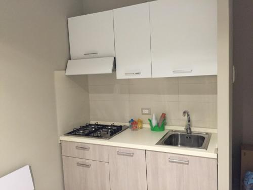 una cocina con armarios blancos y fregadero en Appartamento 403, en Messina