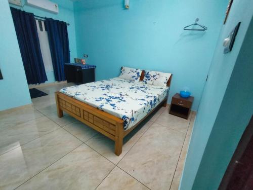 Cama pequeña en habitación con paredes azules en Gerards Home stay Fortkochi en Kochi