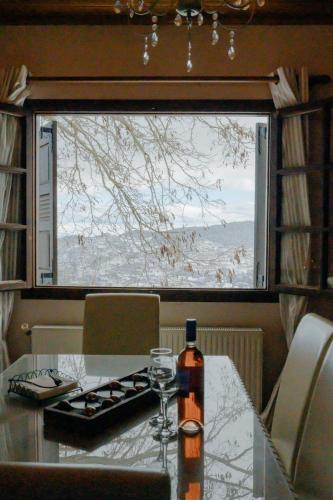 a bottle of wine on a table in front of a window at Παλαιό Λιθάρι in Ano Trikala