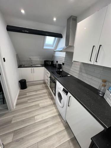 a kitchen with white cabinets and a washer and dryer at Cozy One Bedroom Flat In Bedford - Free Parking & Free WIFI in Bedford