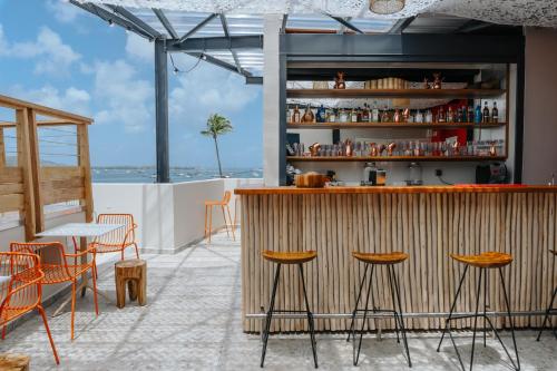 a bar on the rooftop of a restaurant with chairs and tables at Sable Bleu Boutique Hotel in Le Marin