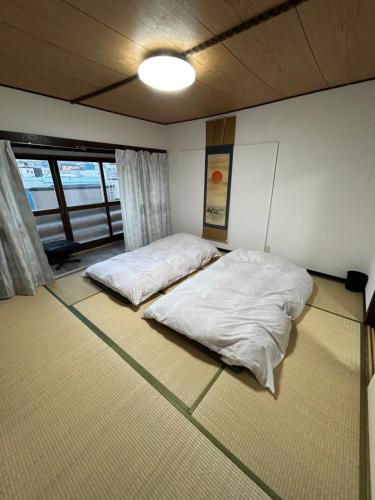 two beds in a room with white sheets at 小樽民泊太田5号館 in Kita-hamachō