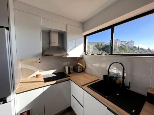 a small kitchen with a sink and a window at Penthouse Terraço de Coimbra in Coimbra