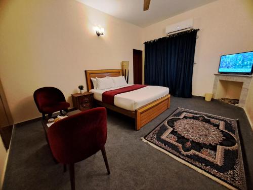 a bedroom with a bed and a chair and a television at La casa Luminosa Hotel in Islamabad