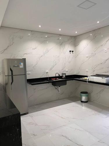 uma cozinha com paredes em mármore branco e um frigorífico em Casa com piscina completa no ABC em São Bernardo do Campo