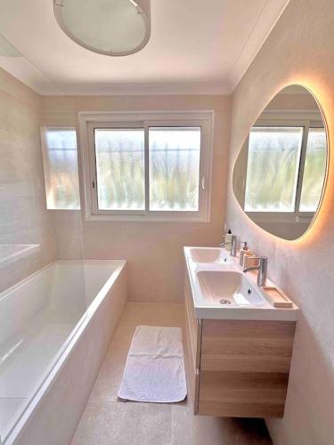 une salle de bain avec une baignoire, un lavabo et un miroir dans l'établissement Superbe 6 couchages - 200m de la mer - Terrasse - Climatisation, à Saint-Raphaël