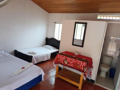 a small room with two beds and a toilet at Hostal Sol de Verano Doña Lilia in Villavieja