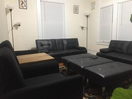 a living room with black leather couches and a table at Comfy 4 Bed 1 Bath w/ Wi-fi in College Area in Springfield