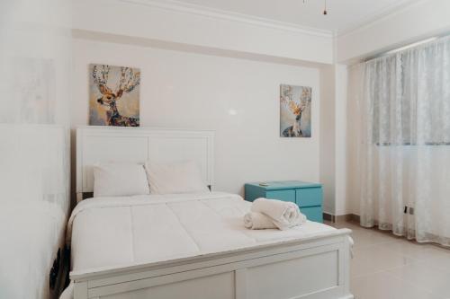 a white bedroom with a white bed and a window at Oceanfront 3 Bedroom With Jacuzzi and Pool in Santo Domingo