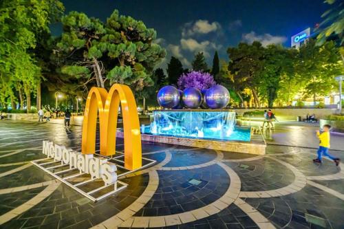 een McDonalds bord in een park 's nachts bij View Nizami Street Chapman Taylor Baku in Baku