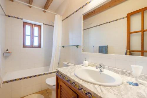 a bathroom with a sink and a toilet and a mirror at La Cubana Casa Vacacional in Banyalbufar