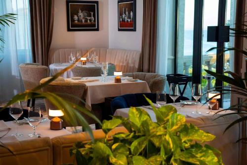 um restaurante com mesas e cadeiras brancas e janelas em Grande Real Villa Itália Hotel & Spa em Cascais