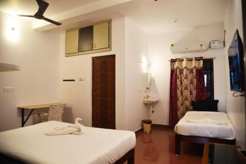 een kamer met 2 bedden, een tafel en een spiegel bij Cardiff palace in Pondicherry