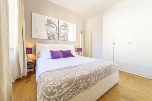 een slaapkamer met een groot wit bed met paarse kussens bij Bright Santa Croce in Florence
