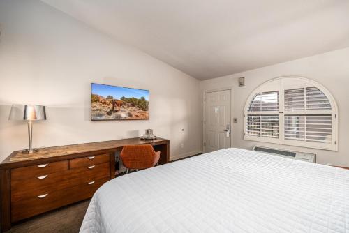 a bedroom with a bed and a desk and a window at Red Mountain Resort in St. George