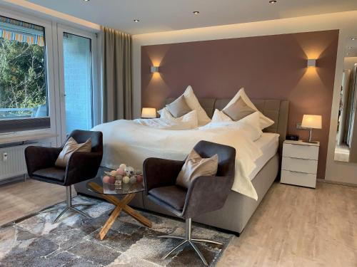 een slaapkamer met een groot bed en 2 stoelen bij Luxusferienwohnung-|-Koehnke-7 in Hahnenklee-Bockswiese