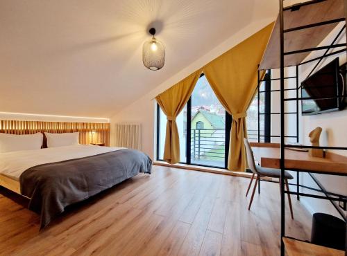 a bedroom with a bed and a desk and windows at RaHouse - Self Check-in & Free Parking in Braşov