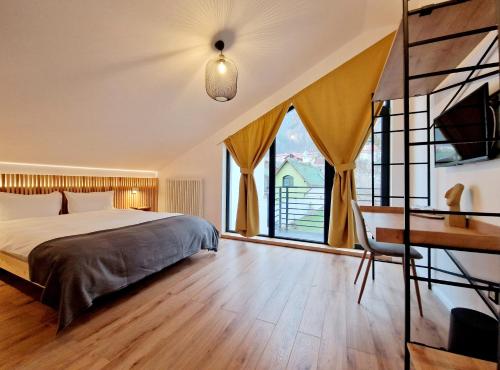 a bedroom with a bed and a desk and windows at RA House in Braşov