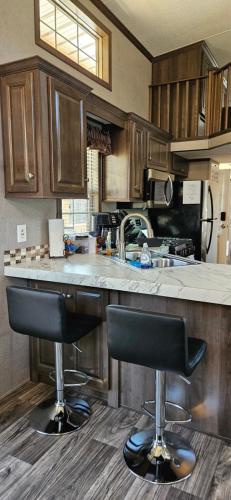 a kitchen with a counter and two bar stools at Tiny home with hammock loft BBQ and yard in Phenix City