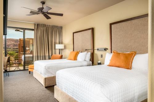 two beds in a hotel room with a balcony at Red Mountain Resort in St. George