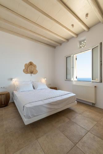 a white bedroom with a large bed and a window at La Chapelle Ouest in Agios Romanos