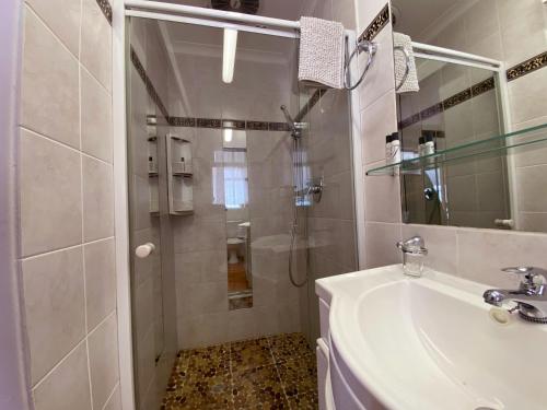 a white bathroom with a shower and a sink at Le Bay Lodge in Gordonʼs Bay