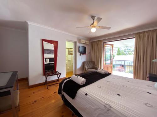 a bedroom with a large bed with a ceiling fan at Le Bay Lodge in Gordonʼs Bay