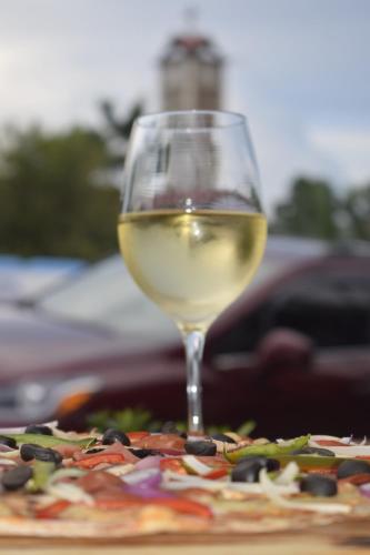 a glass of white wine next to a pizza at Hotel La Vid La Fortuna in Fortuna