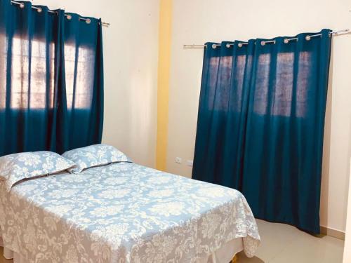 a bedroom with blue curtains and a bed in a room at Grande y acogedor apartamento cerca de la playa. in Azua de Compostela