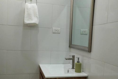 W białej łazience znajduje się umywalka i lustro. w obiekcie loft acogedor w mieście Barranquilla