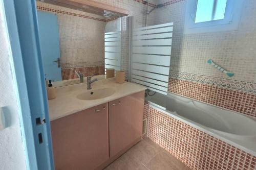 une salle de bain avec un lavabo, une baignoire et un miroir dans l'établissement Gasc, à Valras-Plage