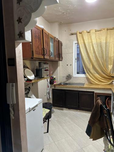 una cocina con armarios de madera y una ventana en appartement familiale, en Meknès