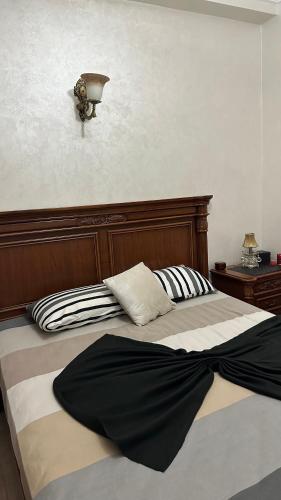 1 cama con cabecero de madera y almohadas en appartement familiale, en Meknès