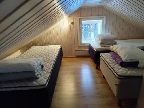 a attic room with three beds and a window at Villa IRIS 3, Himos in Jämsä