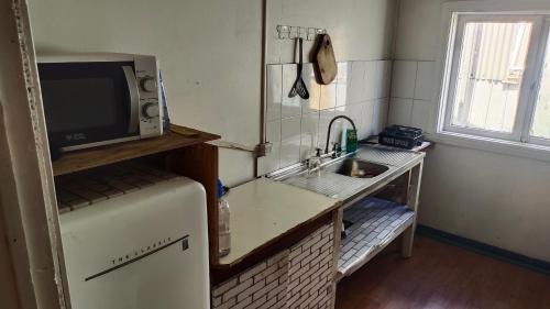 a kitchen with a refrigerator and a sink and a microwave at HOSTAL VALDIVIA in Valdivia