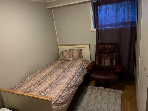 a small bedroom with a bed and a chair at Trondheim, Kroppanmarka Tiller in Trondheim