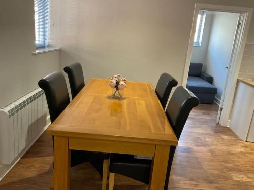 une table en bois avec des chaises et un vase avec des fleurs. dans l'établissement Rest Haven Lodge, à Kettering